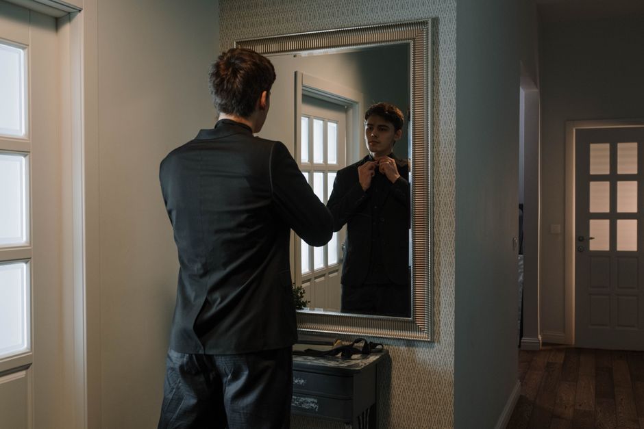 Mann im Anzug betrachtet sein Spiegelbild